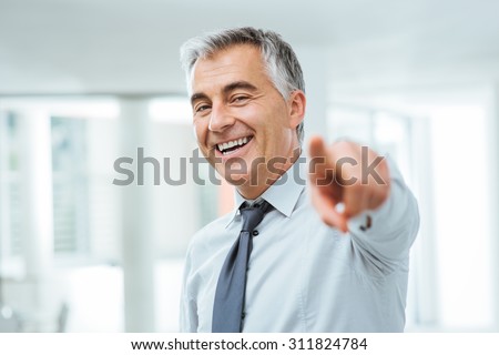 Cheerful confident businessman pointing at camera, recruitment and choice concept