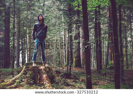 Confident young man standing in the forest, freedom and individuality concept
