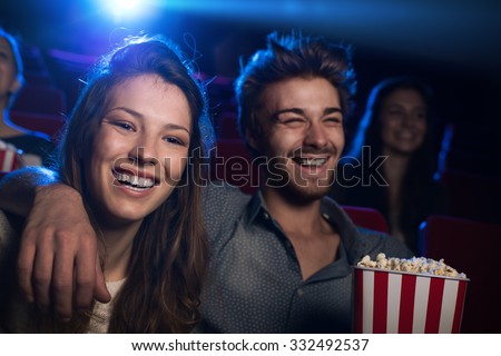Happy young couple in the movie theater watching a film and smiling, entertainment and togetherness concept