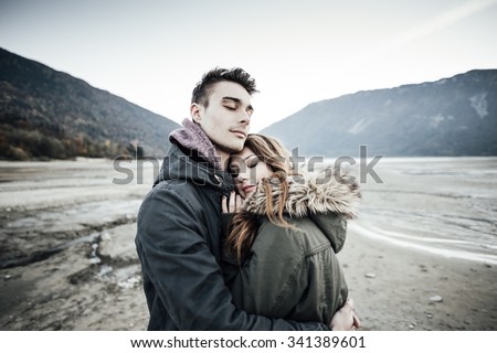 Young loving couple hugging, lake and mountains on background, love and romance concept