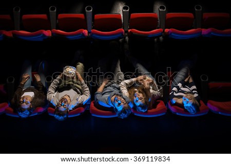 Young happy people in the movie theater having fun, they are looking up and eating popcorn, top view, entertainment and leisure concept