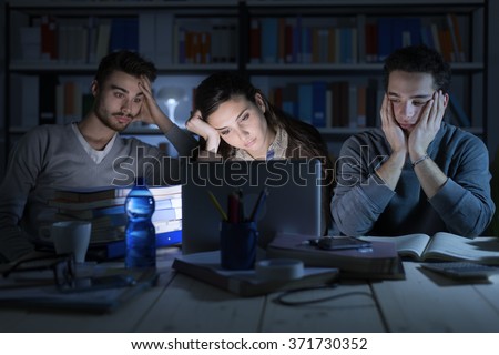 Tired students studying late at night, they are staring at the laptop screen and falling asleep