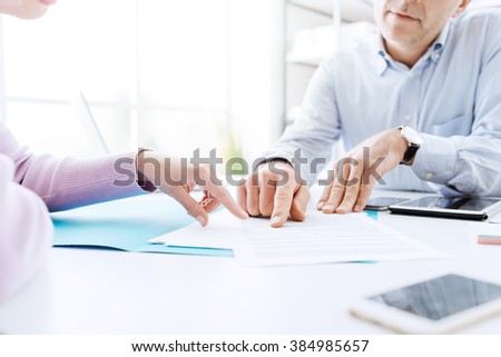 Business people negotiating a contract, they are pointing on a document and discussing together