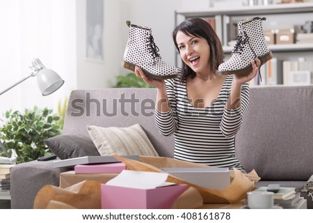 Cheerful young woman at home receiving a parcel with fashion shoes inside, online shopping and delivery concept