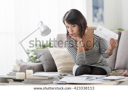 Stressed woman at home checking expensive electricity and household bills, home finance concept
