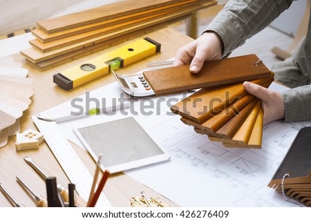 Professional interior designer holding wood swatches for baseboard and skirting, hands close up working at desk