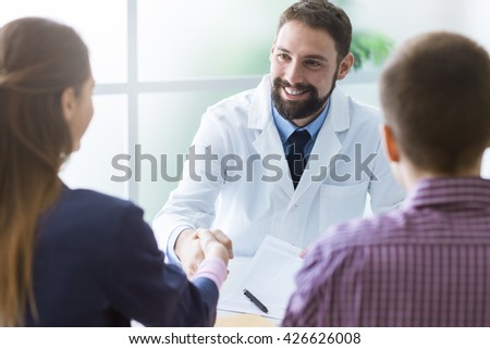 Couple in the doctor\'s office, the doctor is smiling and shaking the woman\'s hand