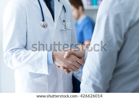 Doctor and patient shaking hands close up, healthcare and assistance concept