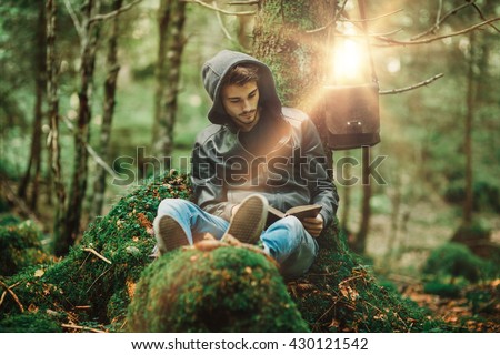Man reading in nature and relaxing outdoors, freedom and individuality concept