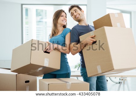 Happy couple staring at each other eyes and carrying boxes in their new house