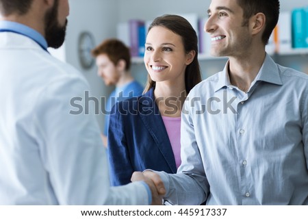 Couple at the doctor\'s office, the doctor is shaking hands with the man, healthcare and consulting concept