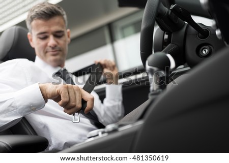 Businessman in his car fastening the seatbelt, safe driving concept
