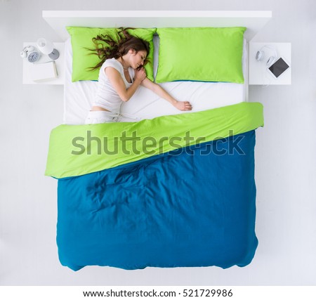 Young woman sleeping in her bedroom, she is resting and dreaming, top view