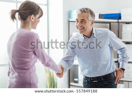Happy young candidate shaking hands with her employer after a job interview, employment and business meetings concept