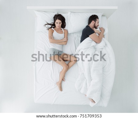 Couple sleeping in bed, the man is stealing the duvet and the woman is angry and freezing