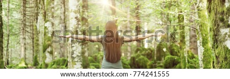 Woman spreading her arms in the forest back view: balance, spirituality and nature concept