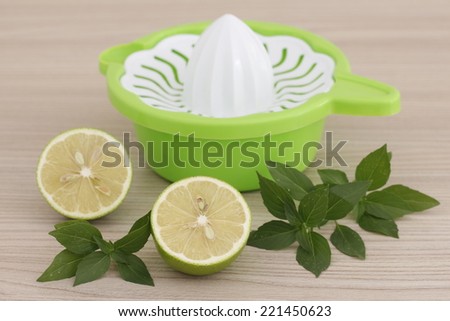 A citrus squeezer with lemon and basil / green lime with fresh basil / lemon / kitchen equipment