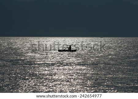 Silhouette of a fishing boat at sunrise out of the coast. Fishing on the sea in the beautiful morning. Fisherman. Silhouette of early morning fishing boat on a sea at dawn.