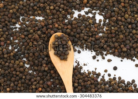 Black pepper on wooden spoon. Black peppercorn background. Black pepper background.