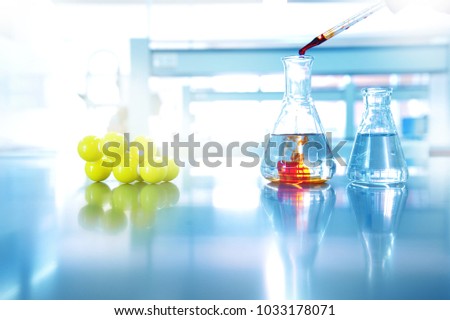 orange drop solution into water in glass flask with chemical yellow structure in science laboratory background