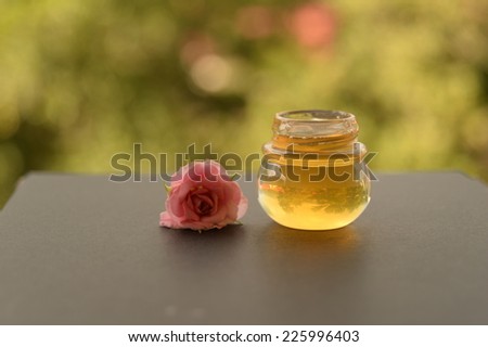 bottle of honey for health ans cosmetic with one of pink rose