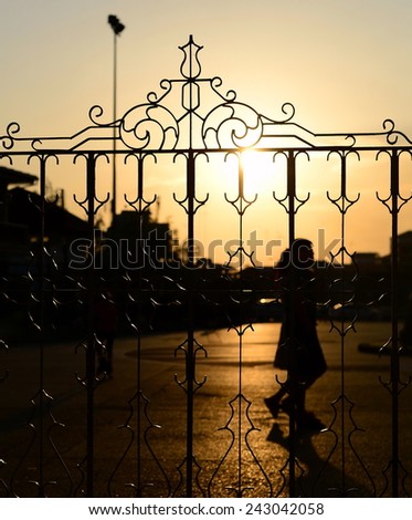 silhouette walking couple behind decorative metal fence at sunset
