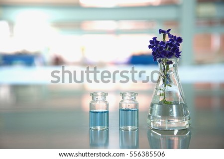 flask and vial with purple flower in science medical laboratory