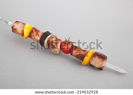 On a white background a skewer with meat and vegetables