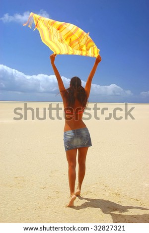 women in desert under the sun and keep scarf in her hands above the head