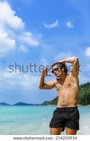 Handsome young man on the beach against the backdrop of the jungle