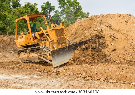 industrial backhoe, bulldozer moving earth and sand in sandpit or quarry