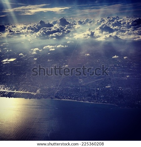An aerial view of the ocean, land, and puffy clouds in the sky.