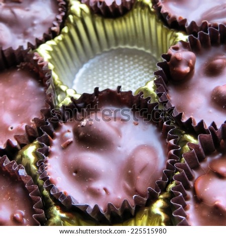 Foil cups of chocolate candies surrounding one empty cup.
