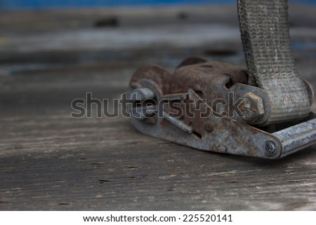 A rusty metal clip sits on a wood table.