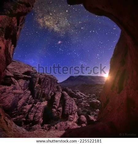 The star-filled night sky seen through a cave entrance.