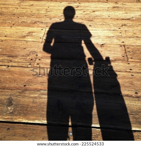 A shadow of a person and skateboard on wooden planks.