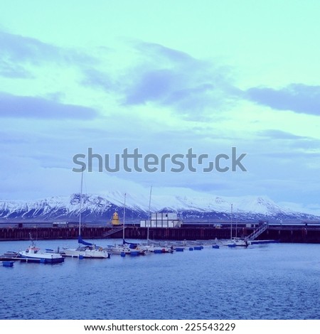Boats lined up with snow capped mountains behind them.