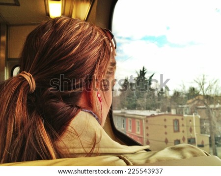 A lady with a pony tail looking out a window.