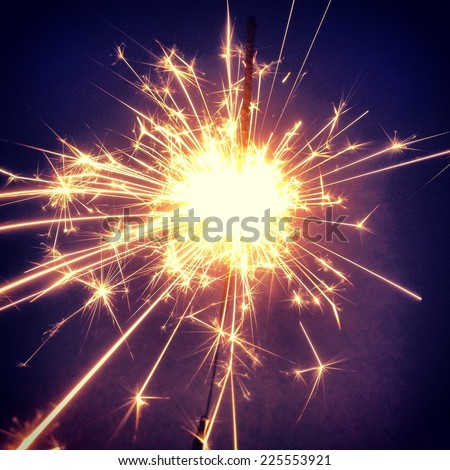 Sparks flying in many directions from a sparkler.