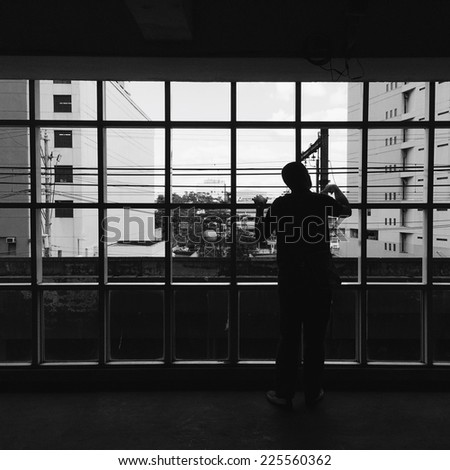 A man standing at a window looking outside.