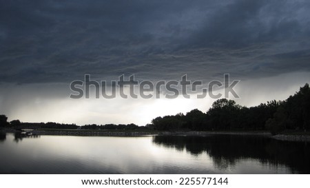 A lake is below a stormy, dark sky.