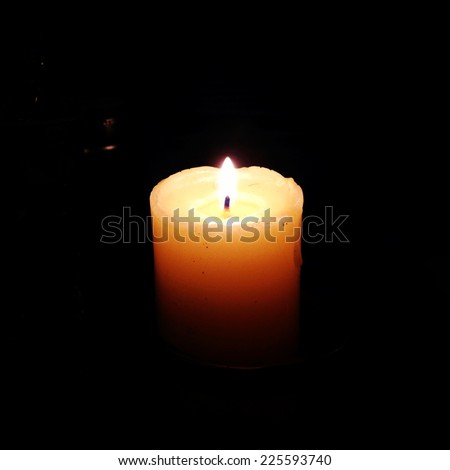 A wax candle burning in the dark night.