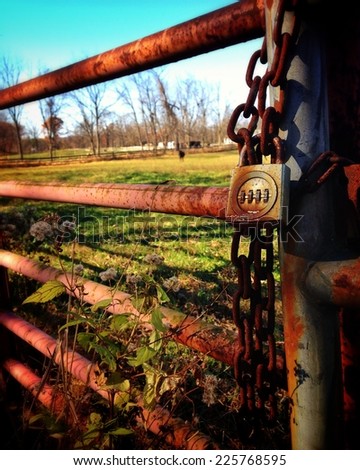 A rusty gate with a combination lock attached to a rusty chain.