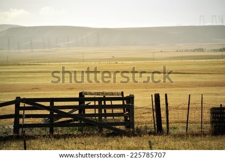 A rolling pasture with a wood and wire fence.