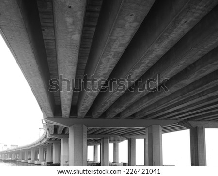A grey bridge supported by thick concrete beams.