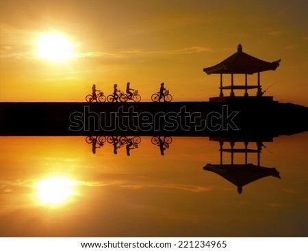 Reflection of cyclists riding on a concrete barrier in bali indonesia Sanur beach at sunrise. This is a great place to visit when you are in Bali ..