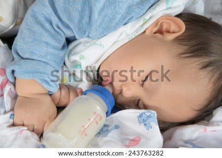 Cute and  adorable Asian baby sleeping .Baby drinking milk from the bottle alone on the bed