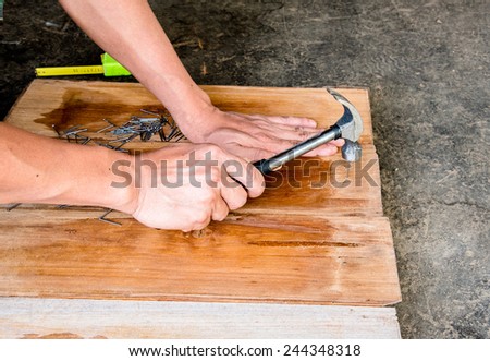 Carpenter nailing the teak wood board by hammer in Thailand to make furniture from old wood