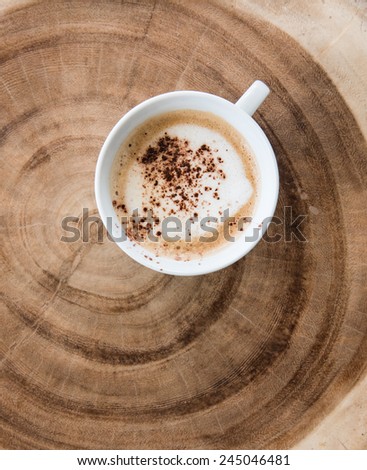 Cappuccino coffee cup on the annual ring wooden table , top view