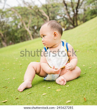 Baby boy play in the garden  , sitting on the green glass field